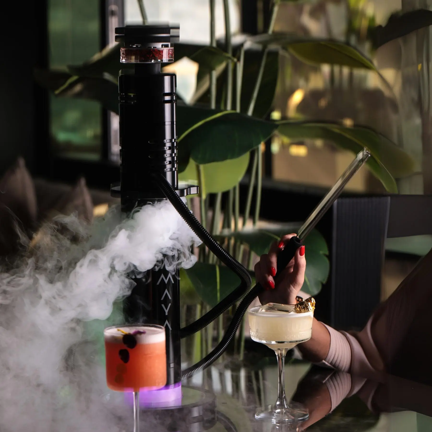 A woman with red nails with shisha pipe in her hand and two drinks