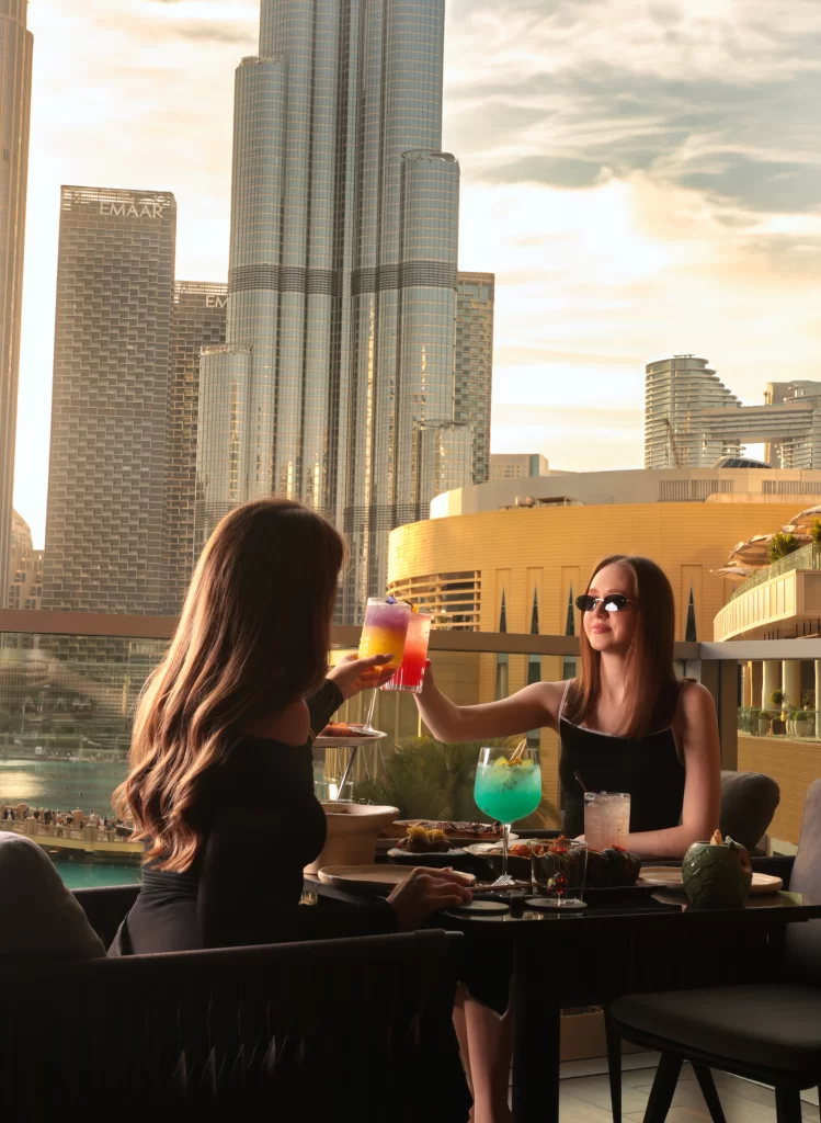 Two women enjoying drinks with Burj Khalifa in the background