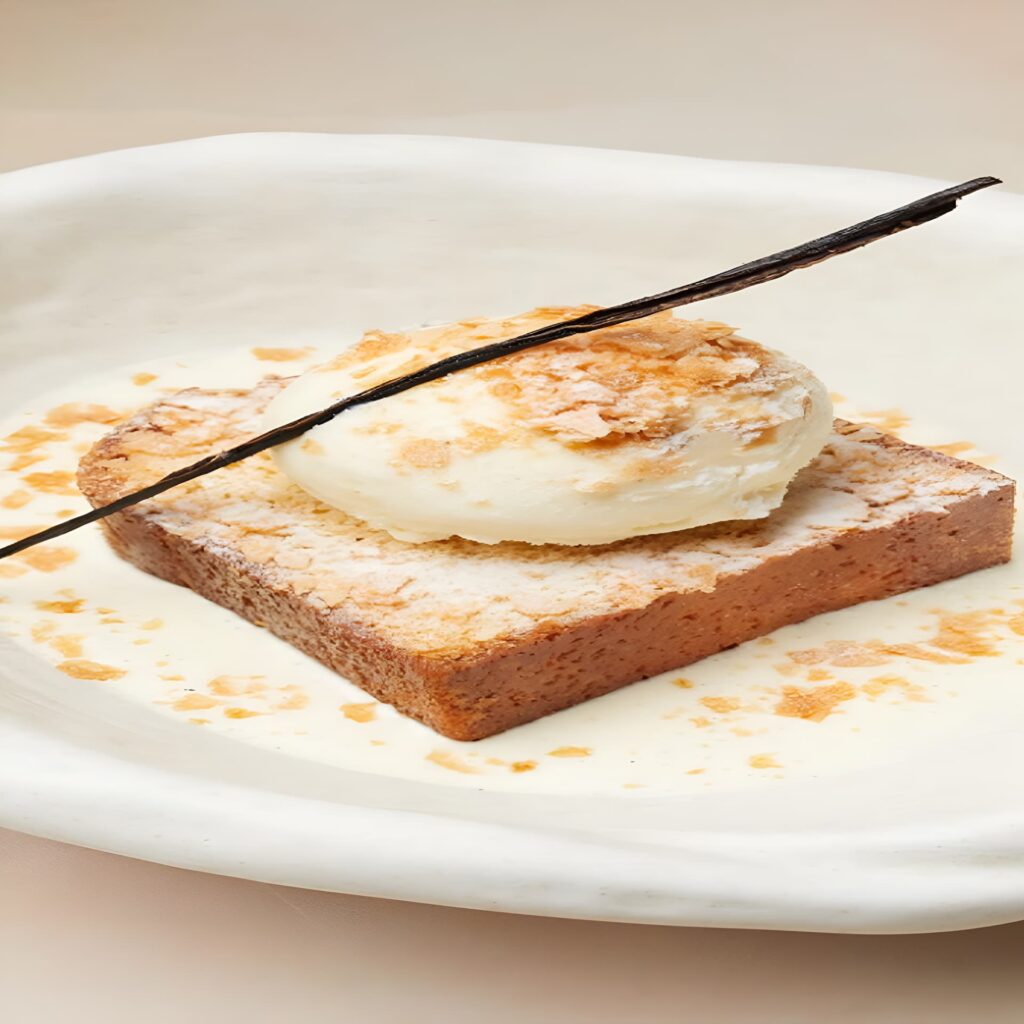 Toasted dessert with cream and vanilla bean garnish.