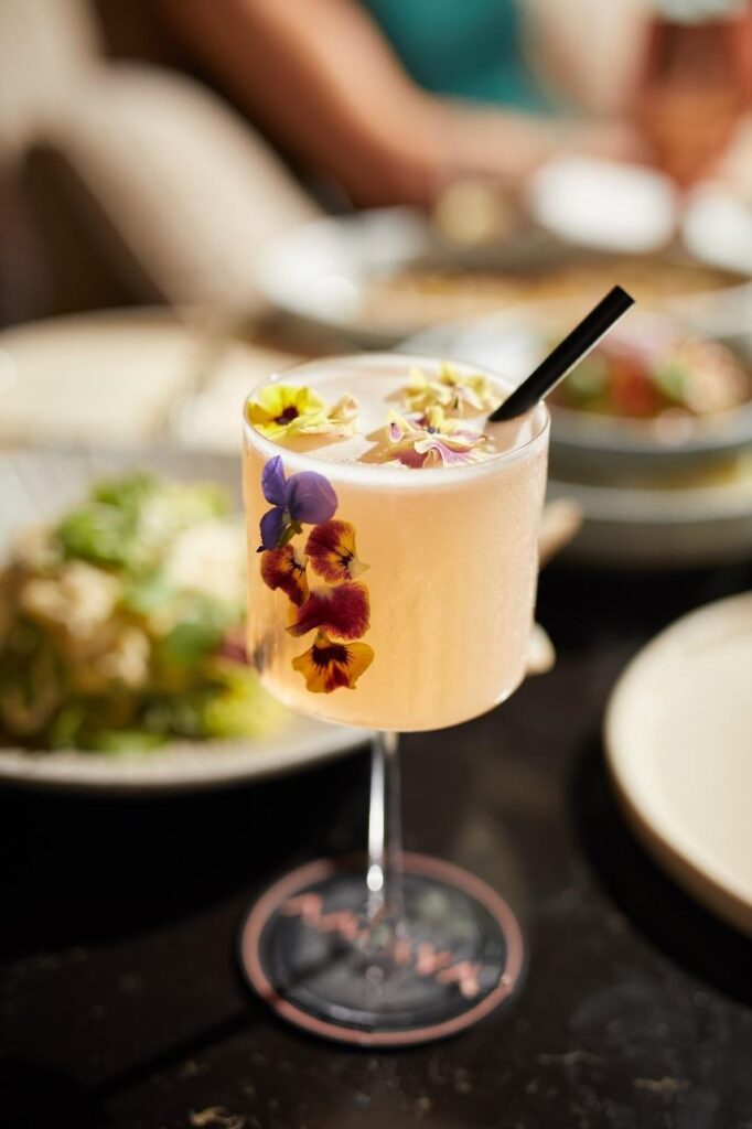 A glass of juice with petals and garnishes